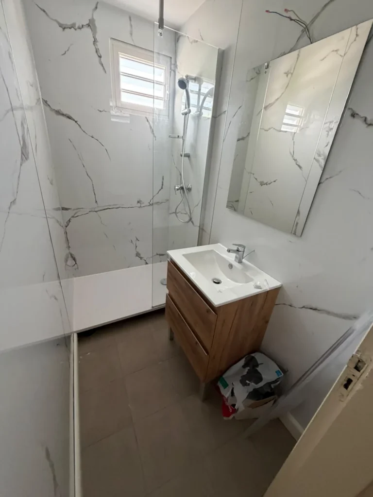 Vue depuis l'entrée d'une salle de bain rénovée à Paradis avec meuble vasque bois